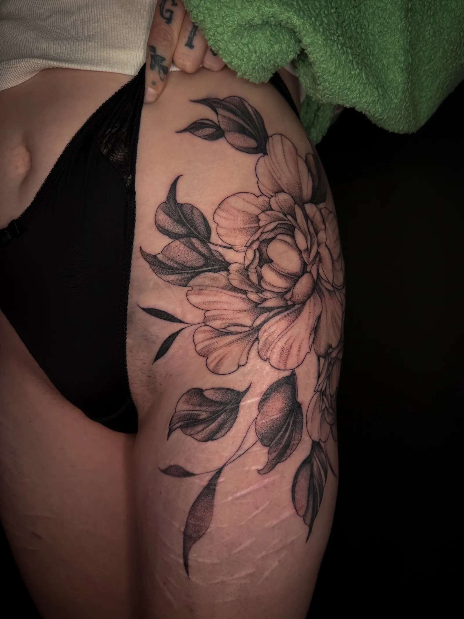 Large fine line peony with trailing leaves across the outer thigh and hip