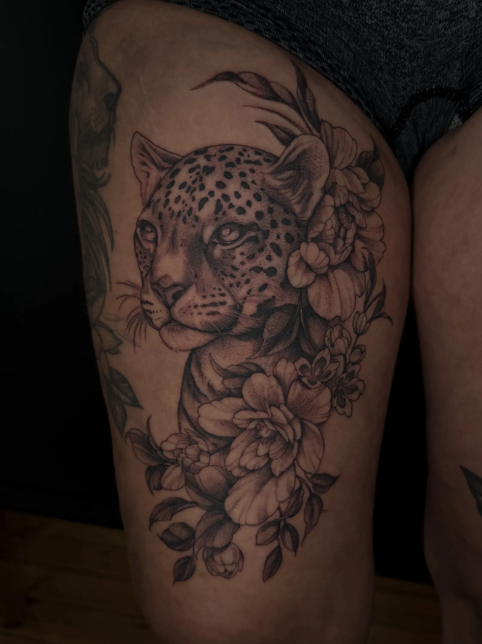 Fine line leopard portrait surrounded by peonies on the thigh